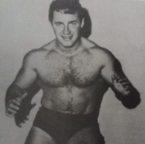 Eddie Sharkey, smiling, posing in black wrestling trunks