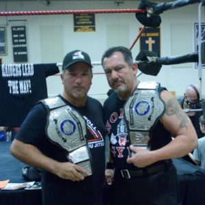 Sam Decero holding Tag Team belts with Mike Anthony